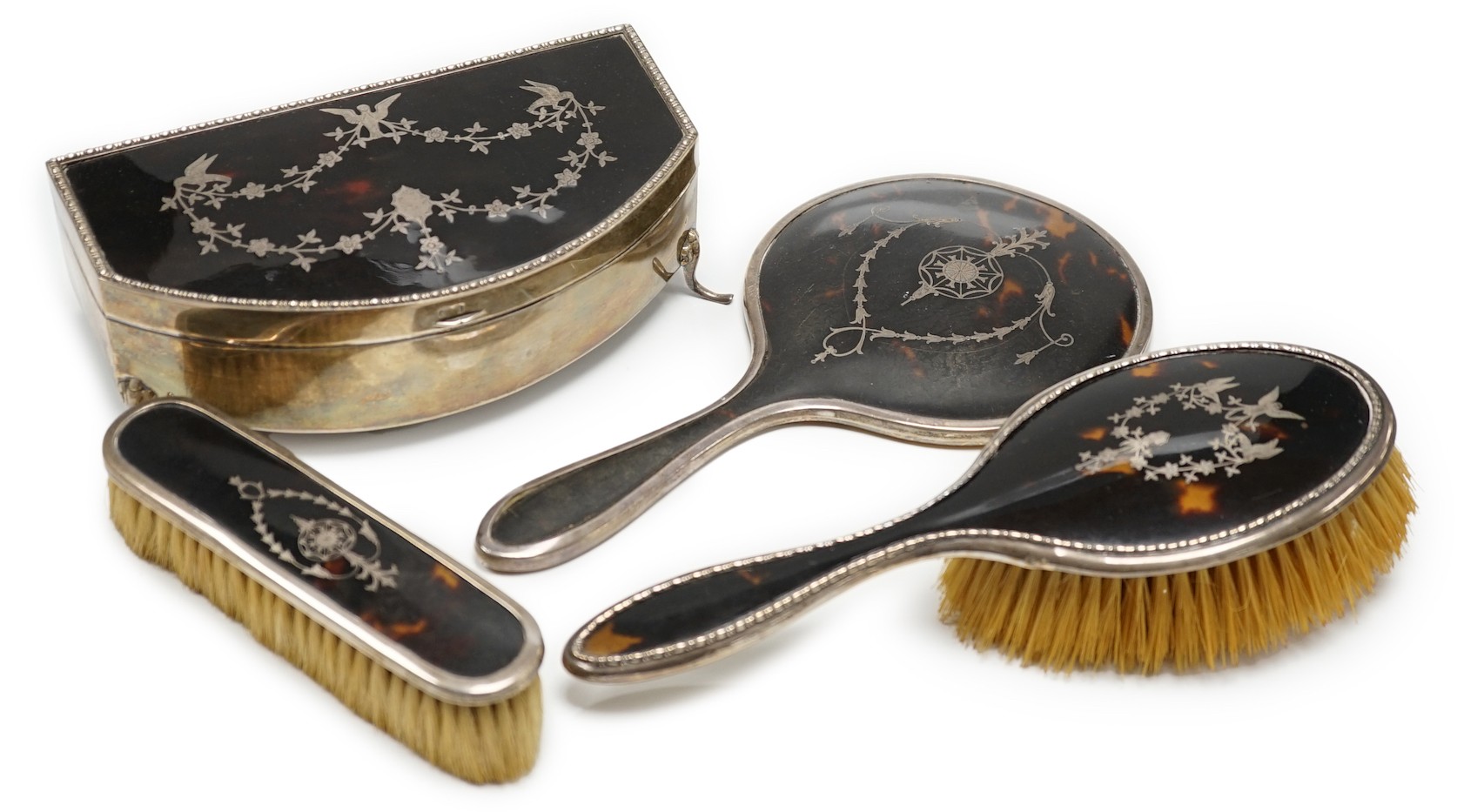 A George V silver and tortoiseshell piqué mounted trinket box, Levi & Salaman, Birmingham, 1918, 19cm and a matched three piece silver and tortoiseshell mounted mirror and brush set.